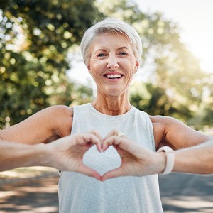 Lady smiles while making shape of heart with her hands