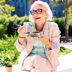 Lady smiles while eating salad