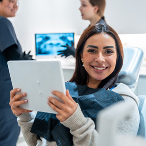 Woman smiling while holding mirror in treatment chair