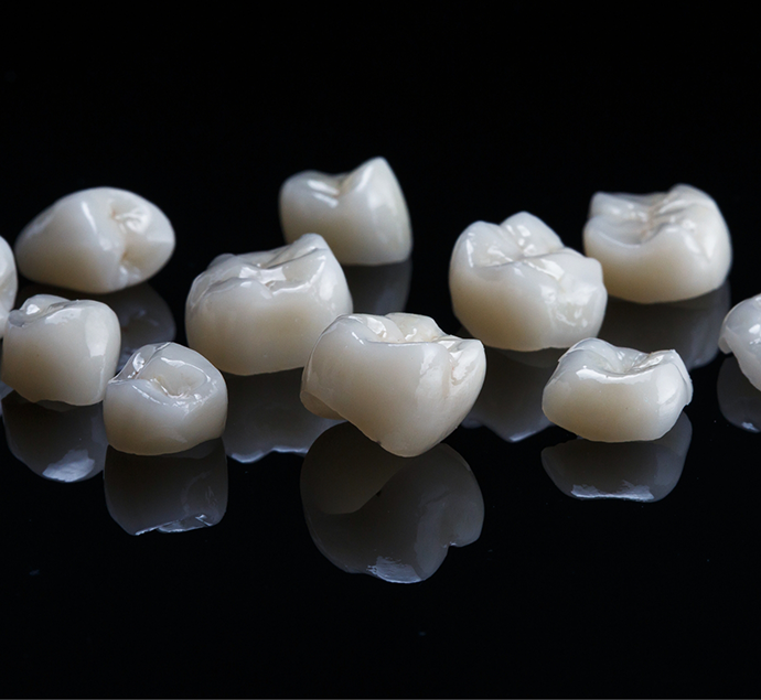 Several tooth colored dental crowns against a black background