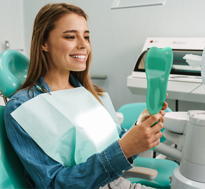 Dental patient looking at her new smile in a mirror