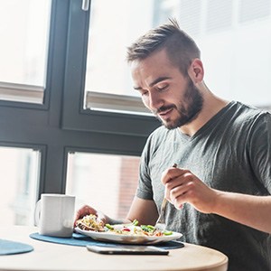 Man at table next to window eating healthy meal