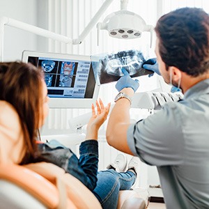 Dentist showing X-rays to patient in dental chair