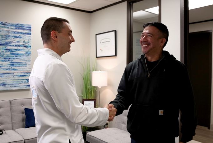 Doctor Pevzner smiling while shaking hands with a male dental patient
