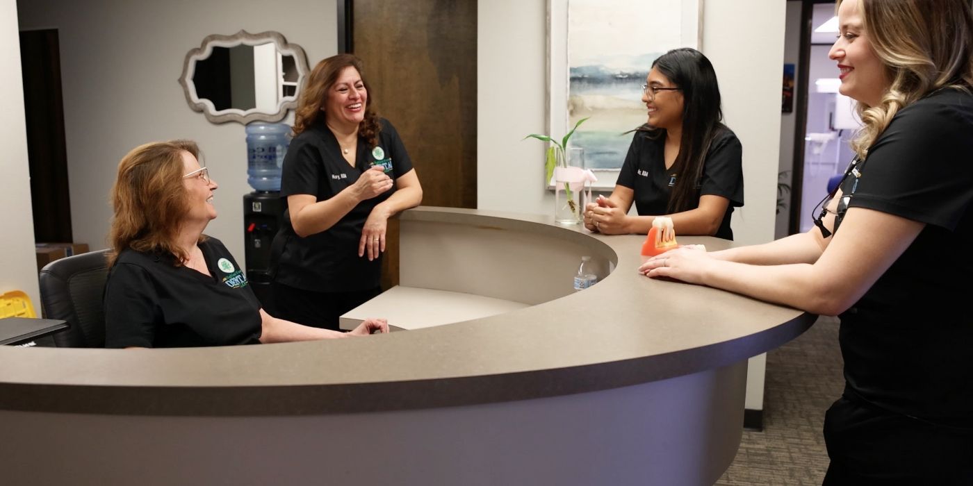 Four Highland West Dental Care team members chatting by the front desk