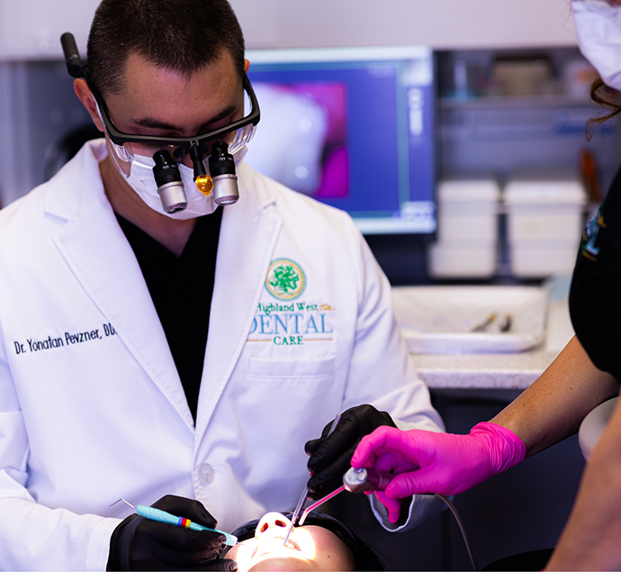 Doctor Yonatan wearing dental binoculars while treating a patient
