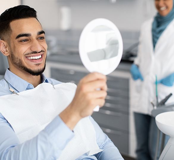 Man smiling at reflection in mirror in treatment chair