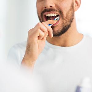 Man smiling while brushing his teeth