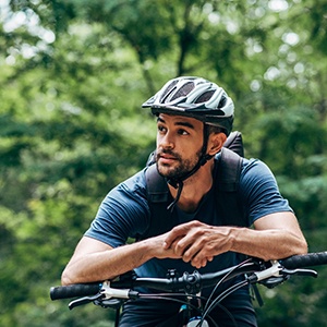 Man with helmet riding bike outside
