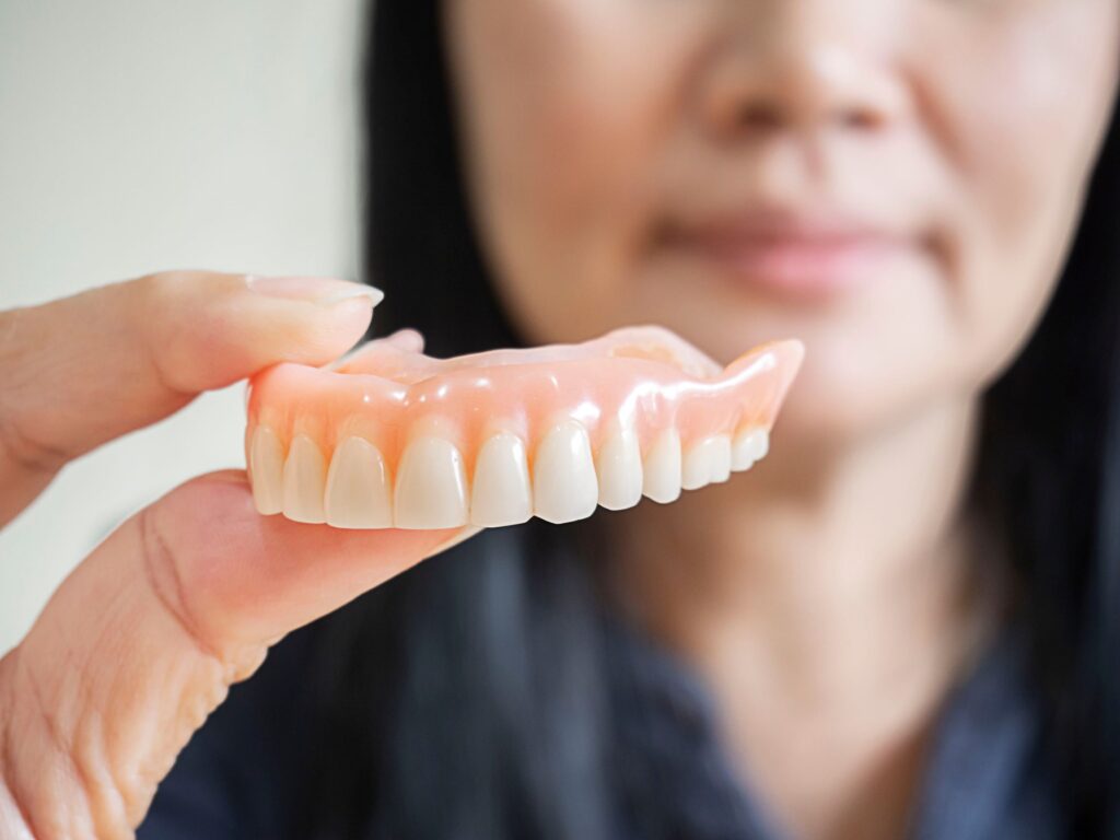 Woman holding upper arch of dentures